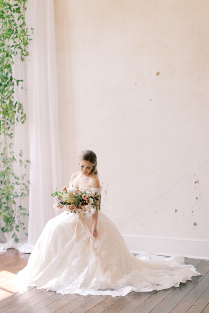 Bride sitting with bouquet of flowers on morning of wedding