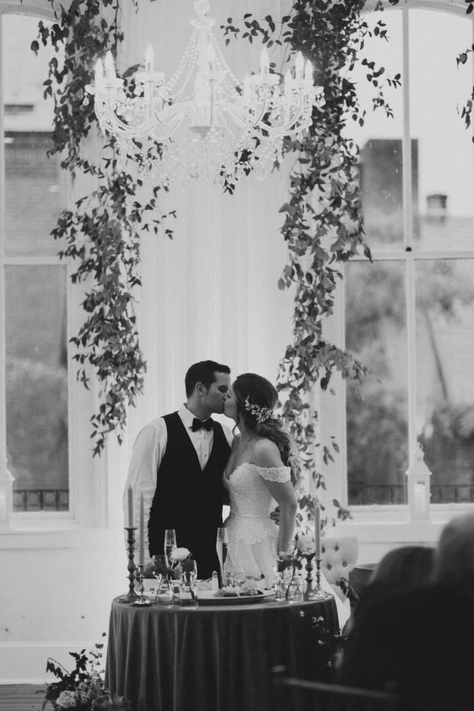 Bride and groom kissing at sweetheart table at wedding reception